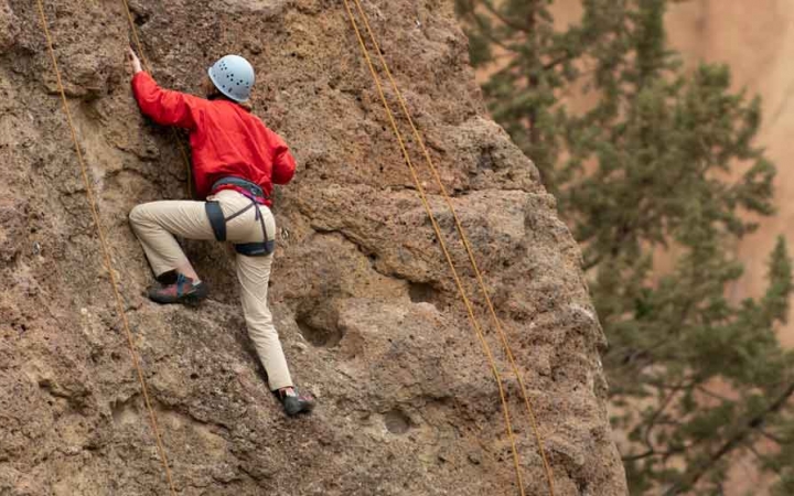 an outward bound student climbs a rock wall on an expedition in the pacific northwest